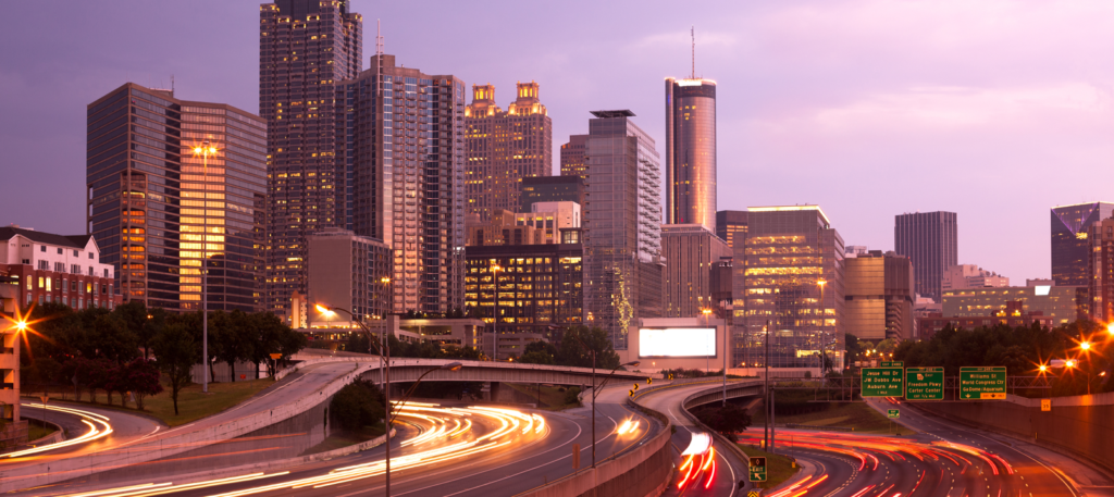 the atlanta skyline with a purple sunset behind it.